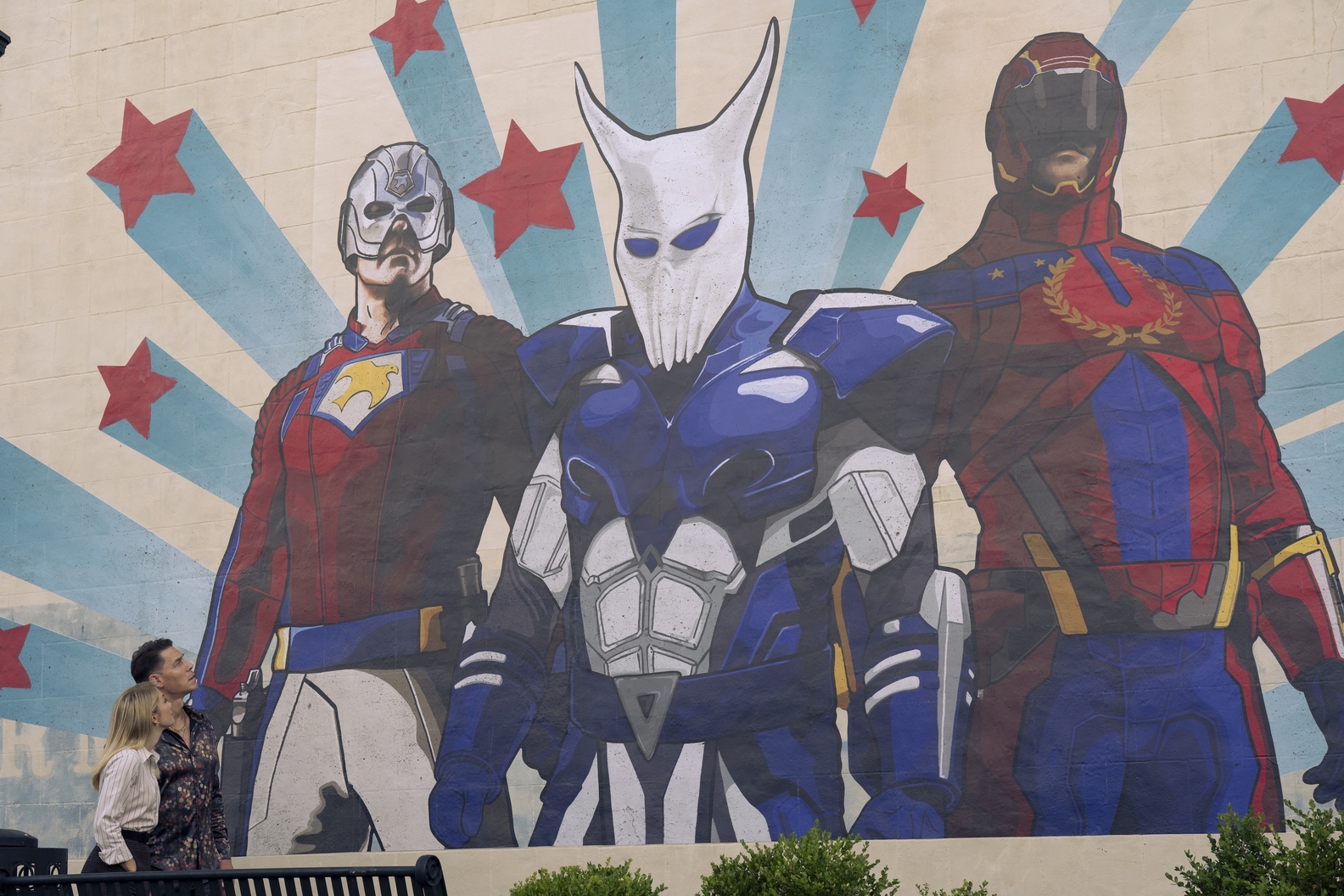 A mural of Earth X’s Top Trio being admired by Chris Smith (John Cena) and Harcourt 2 (Jennifer Holland). HBO MAX/Curtis Bonds Baker